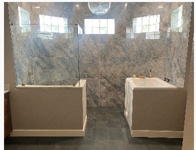Marble-walled master bathroom with soaker tub and walk-in shower