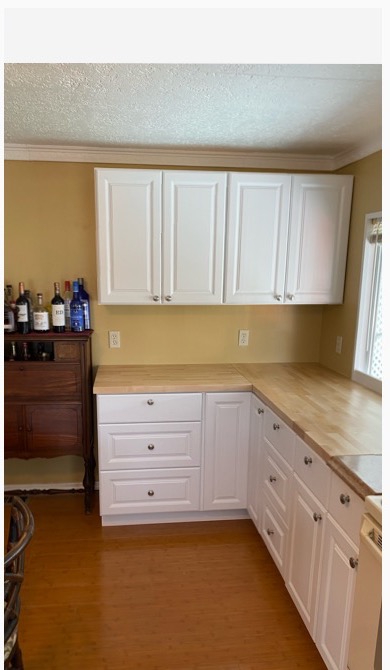 White shaker kitchen with butcher-block counter and bamboo flooring