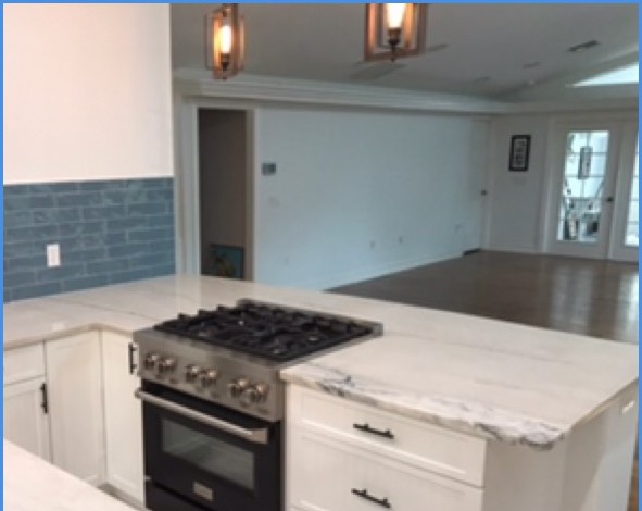 Marble waterfall island with professional gas range and blue subway tile backsplash